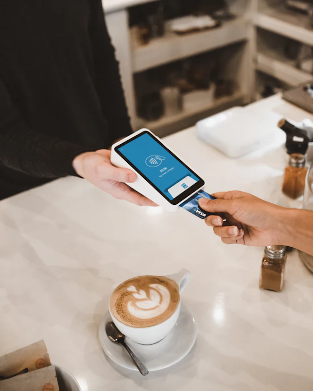 A customer taps a card at a cafe payment terminal