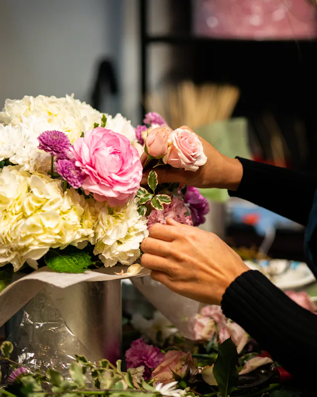 A florist arranges a bouquet at her shop bench
