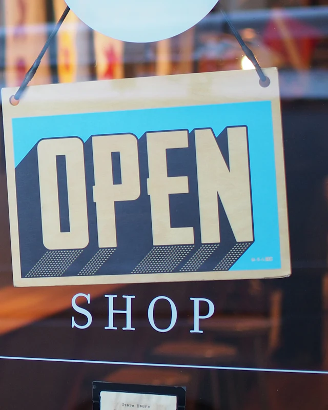 An OPEN sign hangs in a small-business shop door